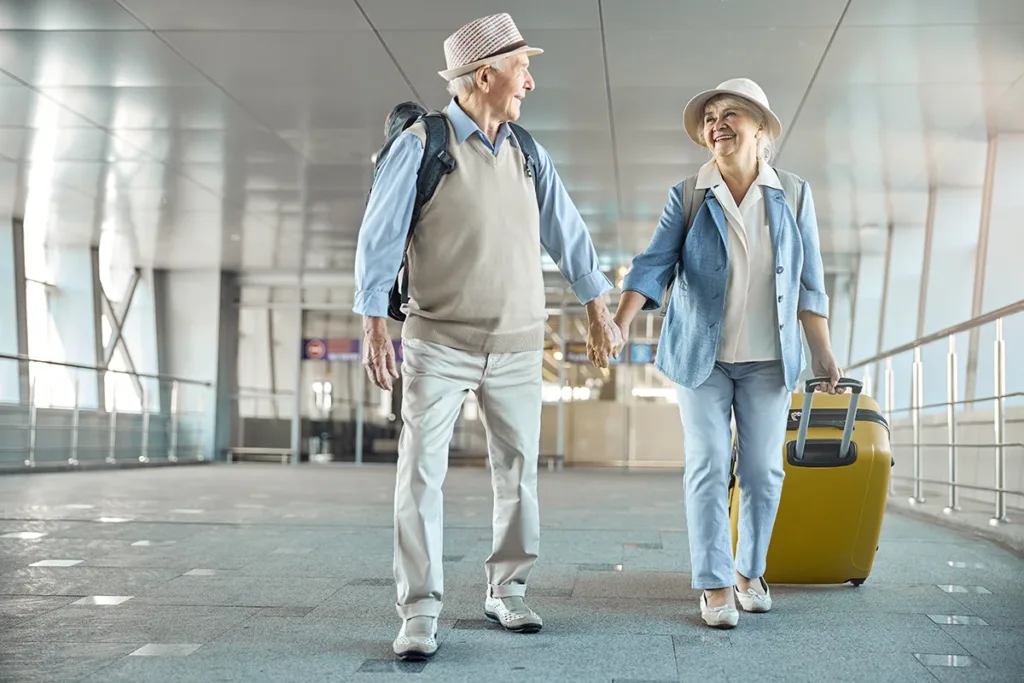 Older couple walking through the airport happy that rechargeable hearing aids make travel and vacations so much easier